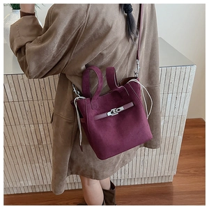 Detail of burgundy suede bucket bag with silver twist lock and white drawstring detail