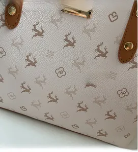 Detailansicht der beigen Tragetasche mit Hirschmuster und braunem Ledergriff-Detail
