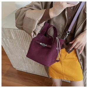 Detail of burgundy suede bucket bag with silver twist lock and stylish drawstring closure