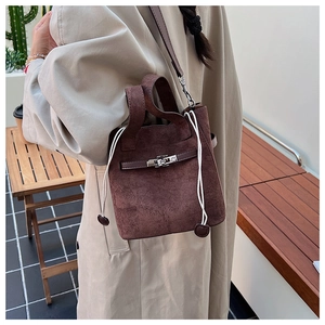 Detail of dark brown suede bucket bag with silver turn-lock and drawstring closure