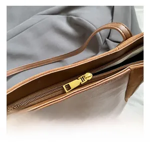 Close-up of golden metal zipper and premium leather stitching on the brown tote bag