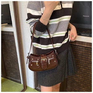 Detail of dark brown patent leather shoulder bag with silver rivets and metal buckle