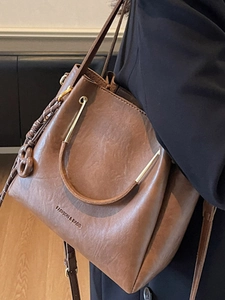 Brown bucket bag in vintage faux leather with gold hardware and fashion lettering