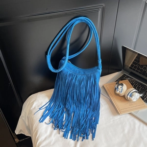 Close-up of royal blue suede shoulder bag featuring long fringe and bohemian retro details