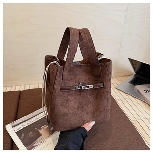 Detail of coffee brown suede bucket bag featuring metallic twist lock and soft texture