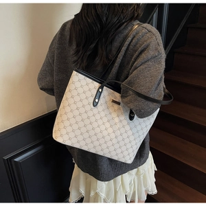 Dettaglio della grande borsa tote crema con stampa geometrica e tracolla nera lucida