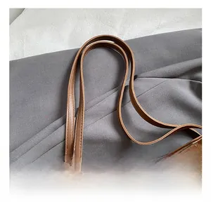 Detail of brown suede tote bag with dual shoulder straps and a cute elephant charm