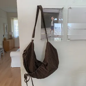 Détail du sac hobo à carreaux marron avec cordon de serrage latéral et texture en tissu doux