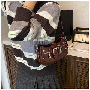 Detail of dark brown patent leather shoulder bag with silver studs and punk metal buckle