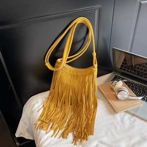 Detail of yellow faux suede fringe bag with long tassels and Bohemian style crossbody strap