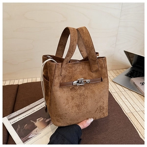 Detail showing suede bucket bag with metal turn-lock and drawstring in warm brown tone