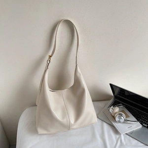 Large cream leather tote bag styled with headphones and laptop for a professional commute