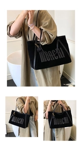 Detail view of large black tote bag featuring distinctive white MORCAI letter embroidery