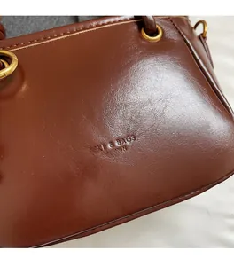 Dettaglio della borsa a secchiello in pelle cerata marrone vintage con logo goffrato