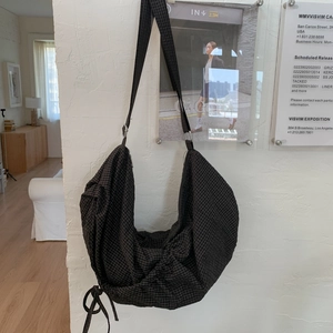 Détail du sac hobo à carreaux noirs avec bandoulière réglable et cordon de serrage