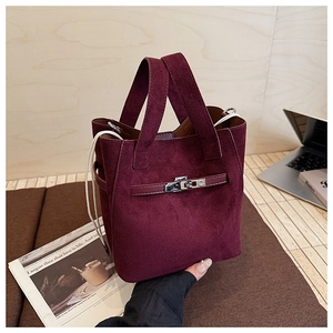 Detail of burgundy suede bucket bag with silver metal lock and drawstring in life setting