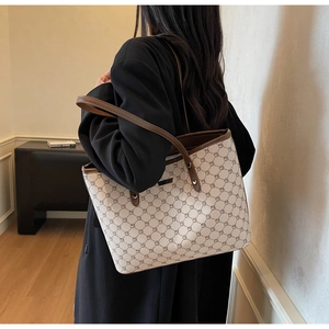 Dettaglio di un'elegante borsa tote con motivi geometrici beige e finiture in pelle marrone