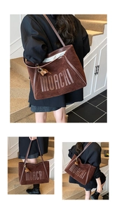 Detail view of large brown suede tote bag with embossed MOACHI lettering and leather strap