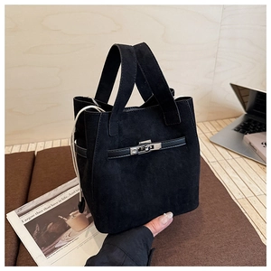 Close-up of black suede bucket bag with metallic twist lock and decorative strap