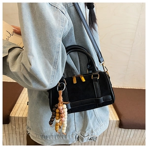 Close-up of black retro Boston bag with beaded tassel and gold dual zippers