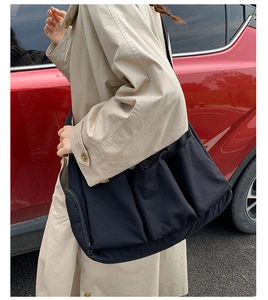 Detail einer großen schwarzen Umhängetasche mit vielen Taschen, getragen von einem Modell