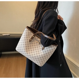 Dettaglio di una grande borsa tote beige con motivi geometrici e manici in cuoio