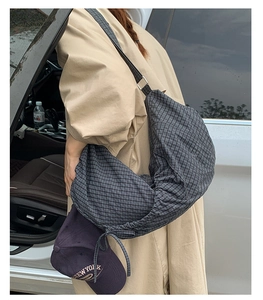 Photo lifestyle d'un grand sac bandoulière à carreaux en forme de croissant avec manteau