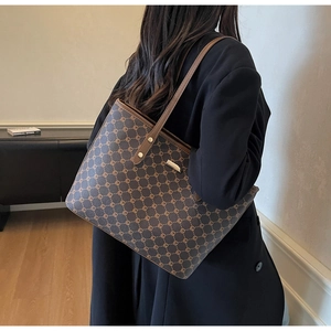 Dettaglio della borsa tote marrone con monogramma indossata da una modella in casa
