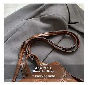 Detail view of the adjustable brown PU leather shoulder strap with embossed texture