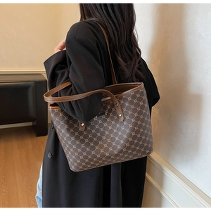 Dettaglio di una borsa tote grande marrone con motivo a catena indossata da una modella
