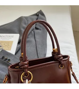 Dettaglio ravvicinato della borsa in pelle marrone scuro con anelli in metallo oro