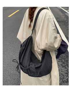 Détail du sac bandoulière à carreaux noir et blanc avec nœuds de serrage décoratifs