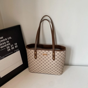Dettaglio della borsa tote beige con motivo geometrico e placca in metallo dorato