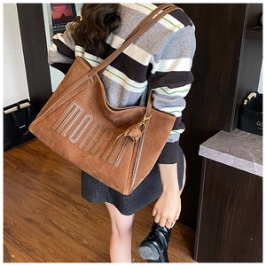 Brown suede tote bag with NORCAH embossed text and decorative tassel detail