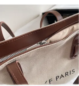 Vue détaillée de la fermeture éclair en métal et des finitions en cuir brun du sac cabas