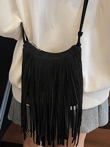 Minimalist black fringe crossbody bag with suede finish and silver zipper on white outfit
