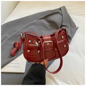 Detail of dark red rivet handbag with silver buckles and zippers for a stylish biker look