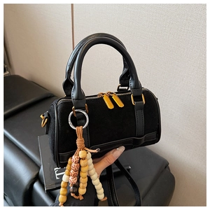 Close-up of black suede mini Boston bag with golden hardware and pearl bead charm