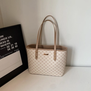 Dettaglio della borsa tote beige con monogramma, manici in pelle e placca dorata