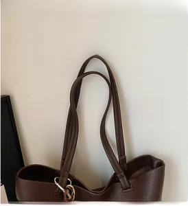 Close-up of the durable handles and litchi texture on the dark brown leather tote bag