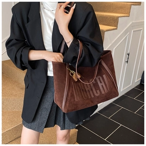 Detailed view of brown suede tote bag featuring embossed MOCHI lettering and long straps