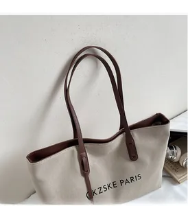 Détail du sac fourre-tout en toile beige minimaliste avec poignées en cuir marron