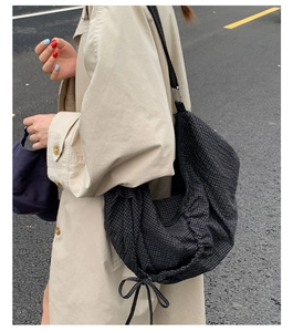 Détail du sac hobo à carreaux noirs avec fermeture à cordon et grande capacité sur l'épaule