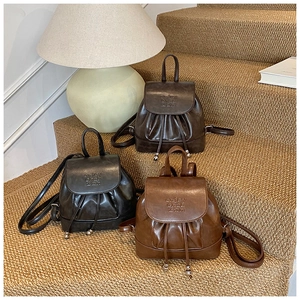 Close-up of vintage mini leather backpacks with drawstring and silver metal ball accents