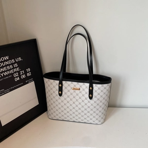 Dettaglio della borsa tote bianco sporco con motivo monogramma grigio e targa in metallo dorato