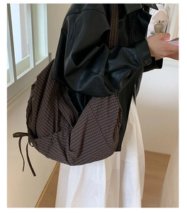 Détail du sac croissant à carreaux avec cordon latéral porté avec une tenue d'automne