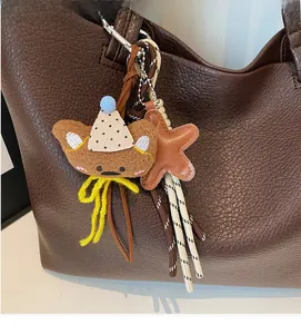 Close-up of a brown plush bear charm with polka dot hat and star on a leather bag