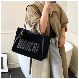 Detail of black suede tote bag featuring white MOACAI stitching and slim shoulder straps
