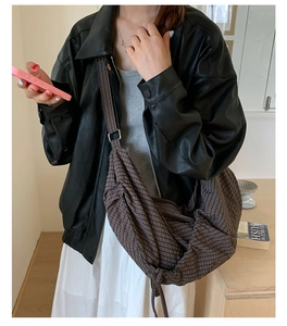Sac hobo marron à carreaux porté par le mannequin avec veste en cuir dans un café