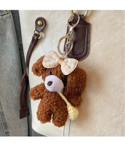 Vue détaillée d'un charm ours en peluche marron avec nœud jaune sur un sac cabas en cuir
